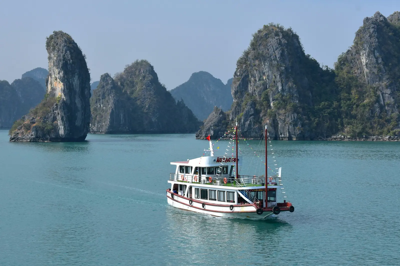 A sightseeing boat among limestone islands in Ha Long Bay.
